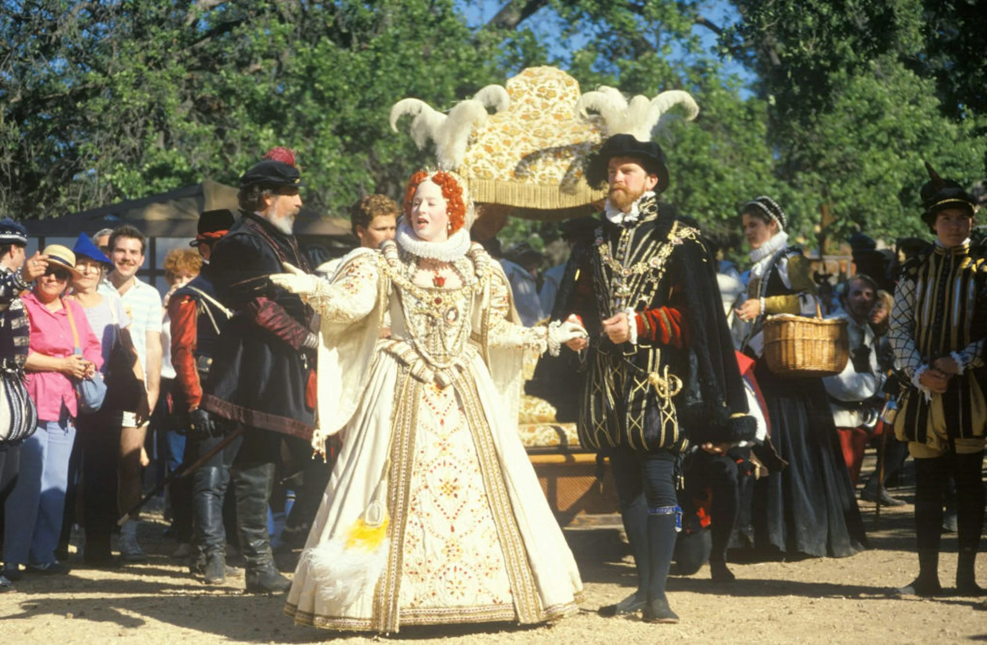 Actors dressed as European royalty from centuries ago perform in front of a crowd of smiling onlookers.