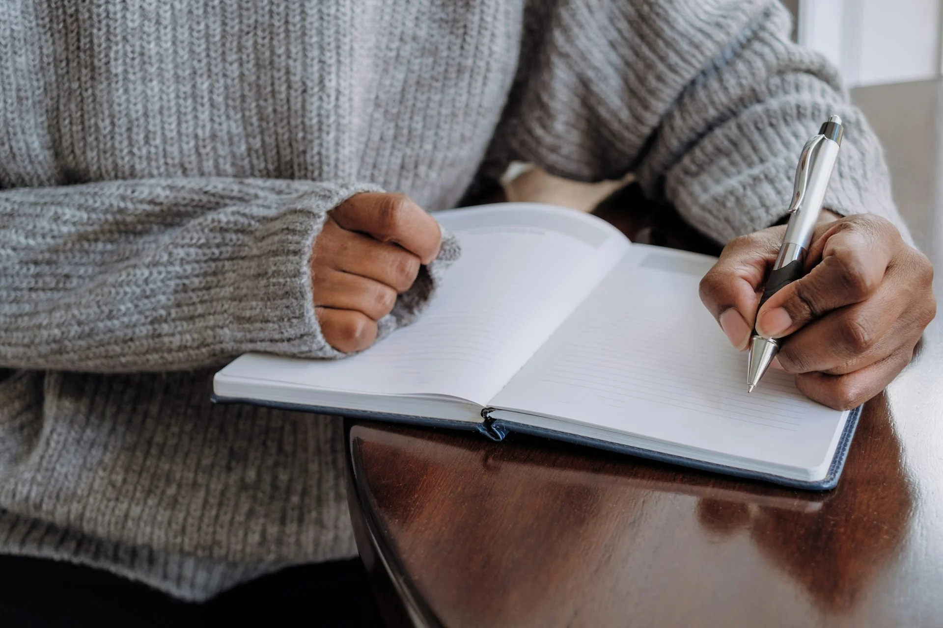 Arms in sweater with hand writing in a journal