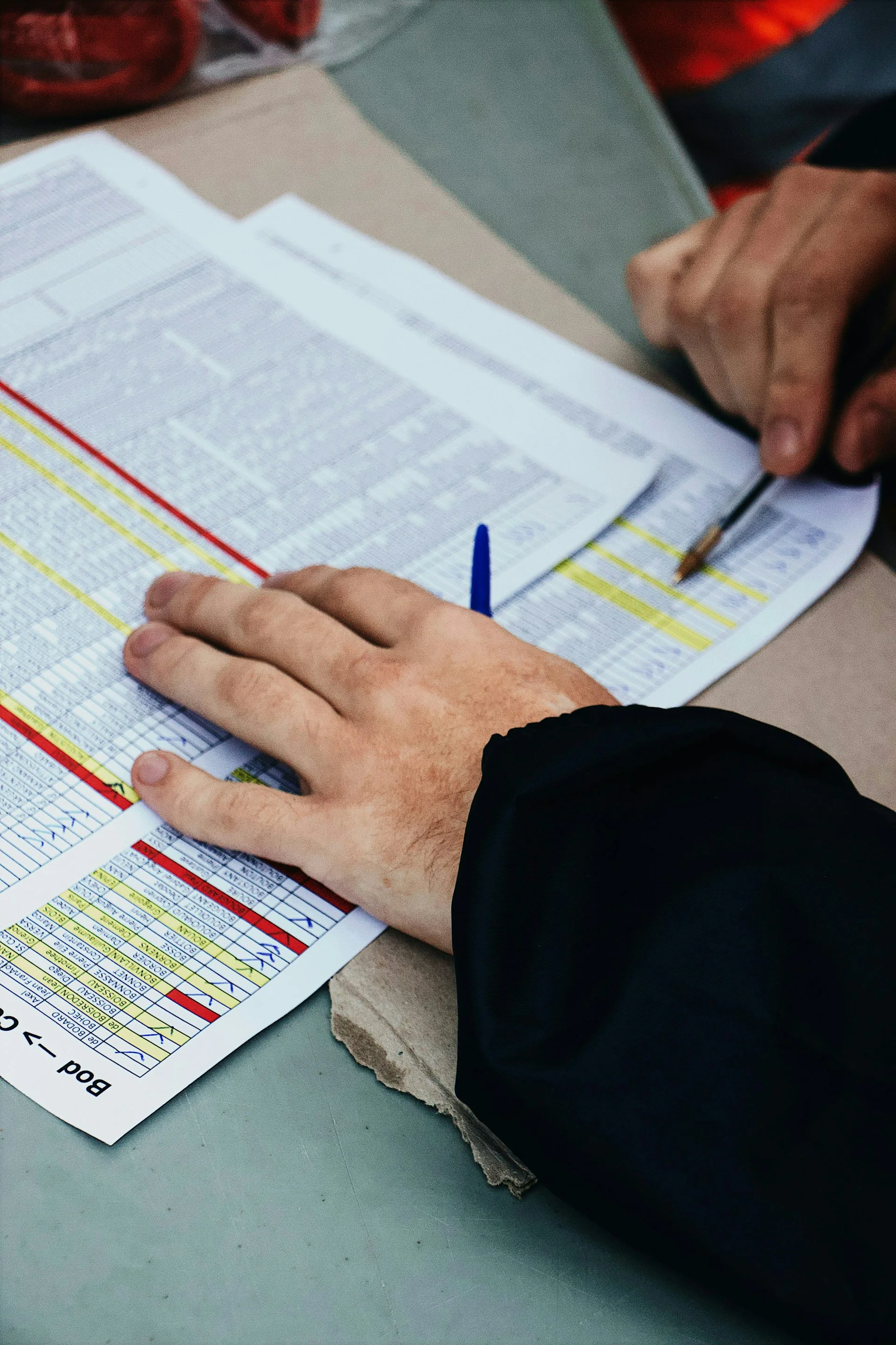 A close-up of a person's hands, with pen in one, going over a complicated medical billing form.